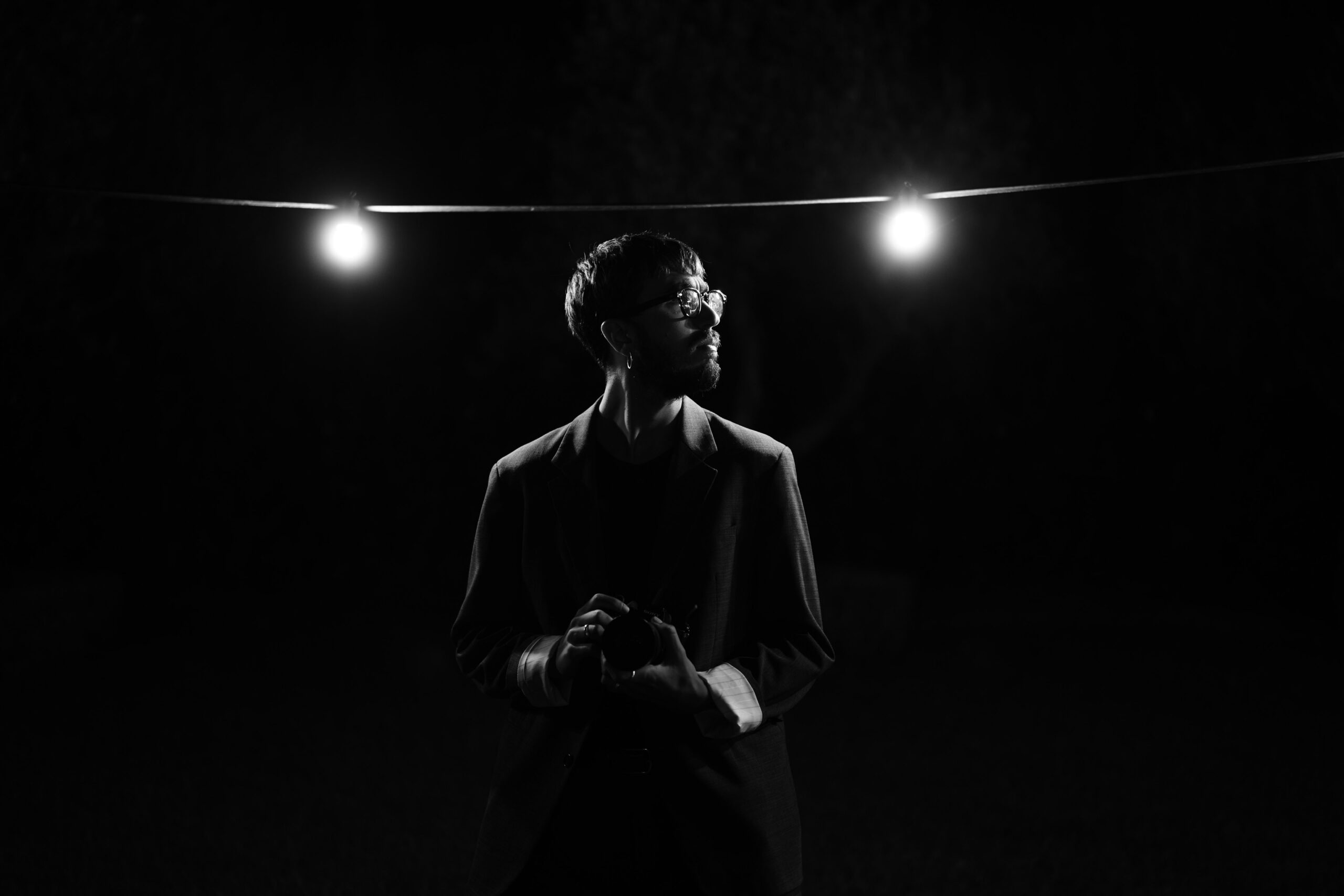 Black and white image of a bride beneath evening lights