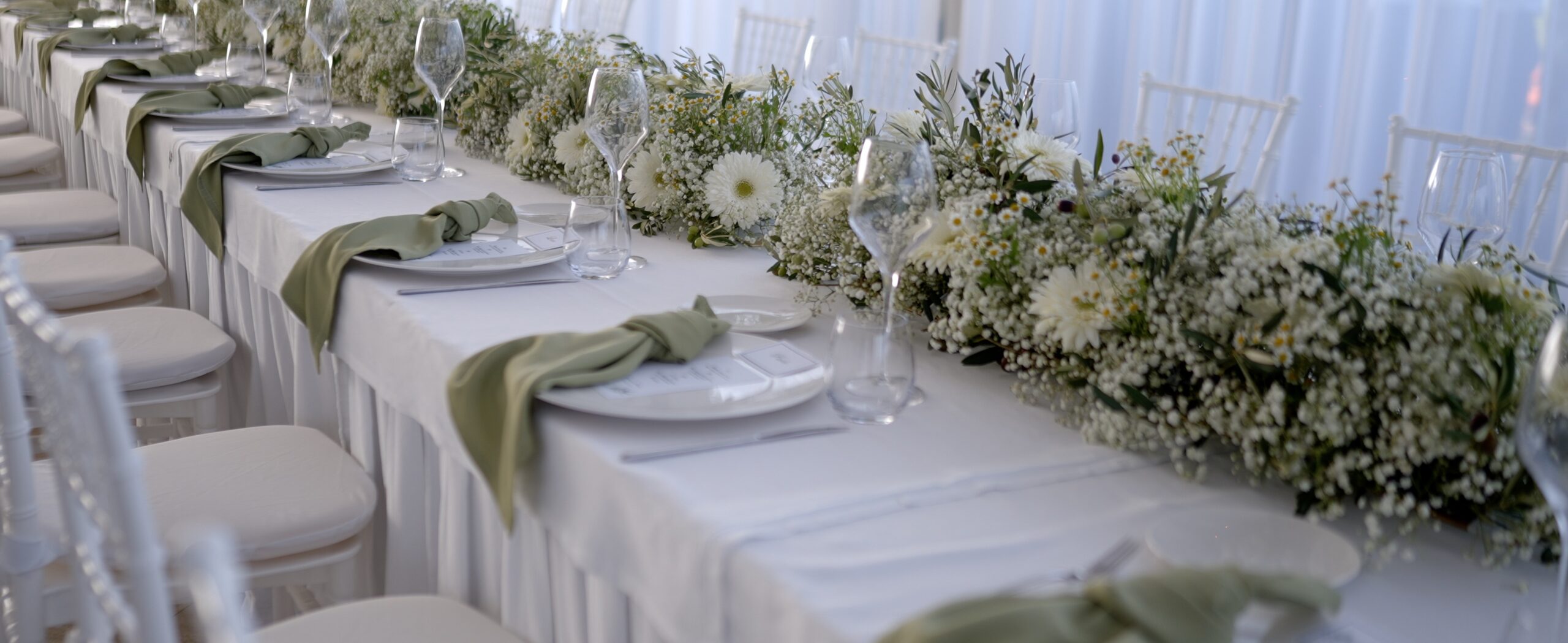 Wedding reception table with white flowers and sage-green napkins