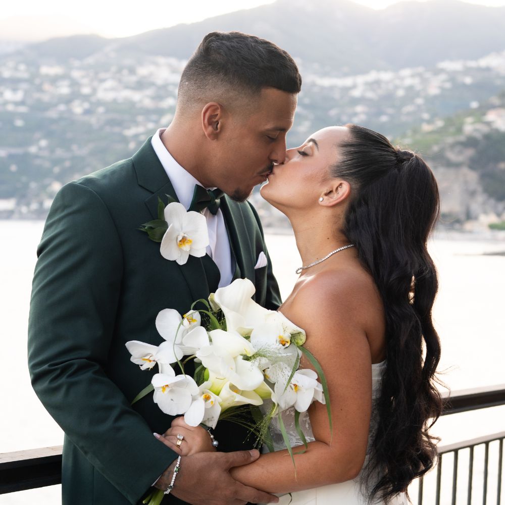 Bride and groom kissing beside a terrace railing