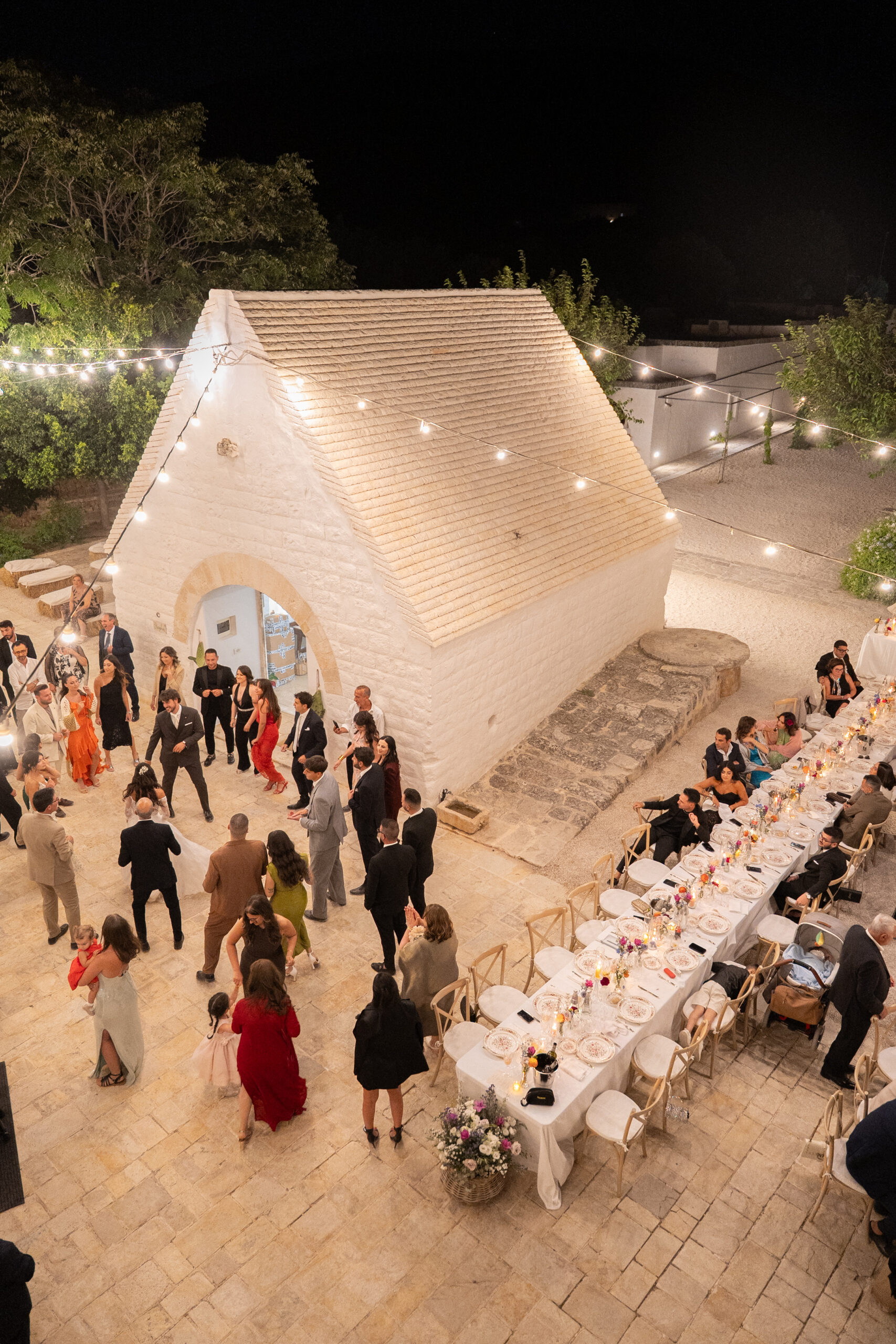 Wedding reception setting at Masseria Capece, with string lights and a large circular decorative light display.