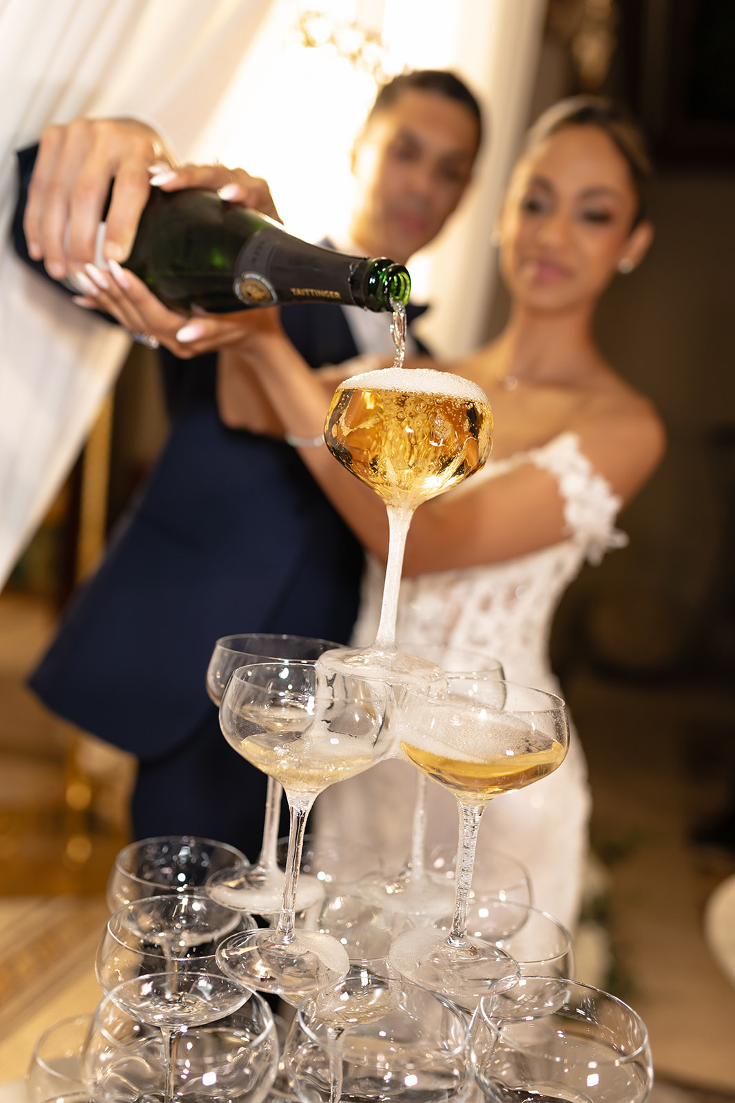 Zeenat pouring champagne into a tower of glasses at her wedding reception