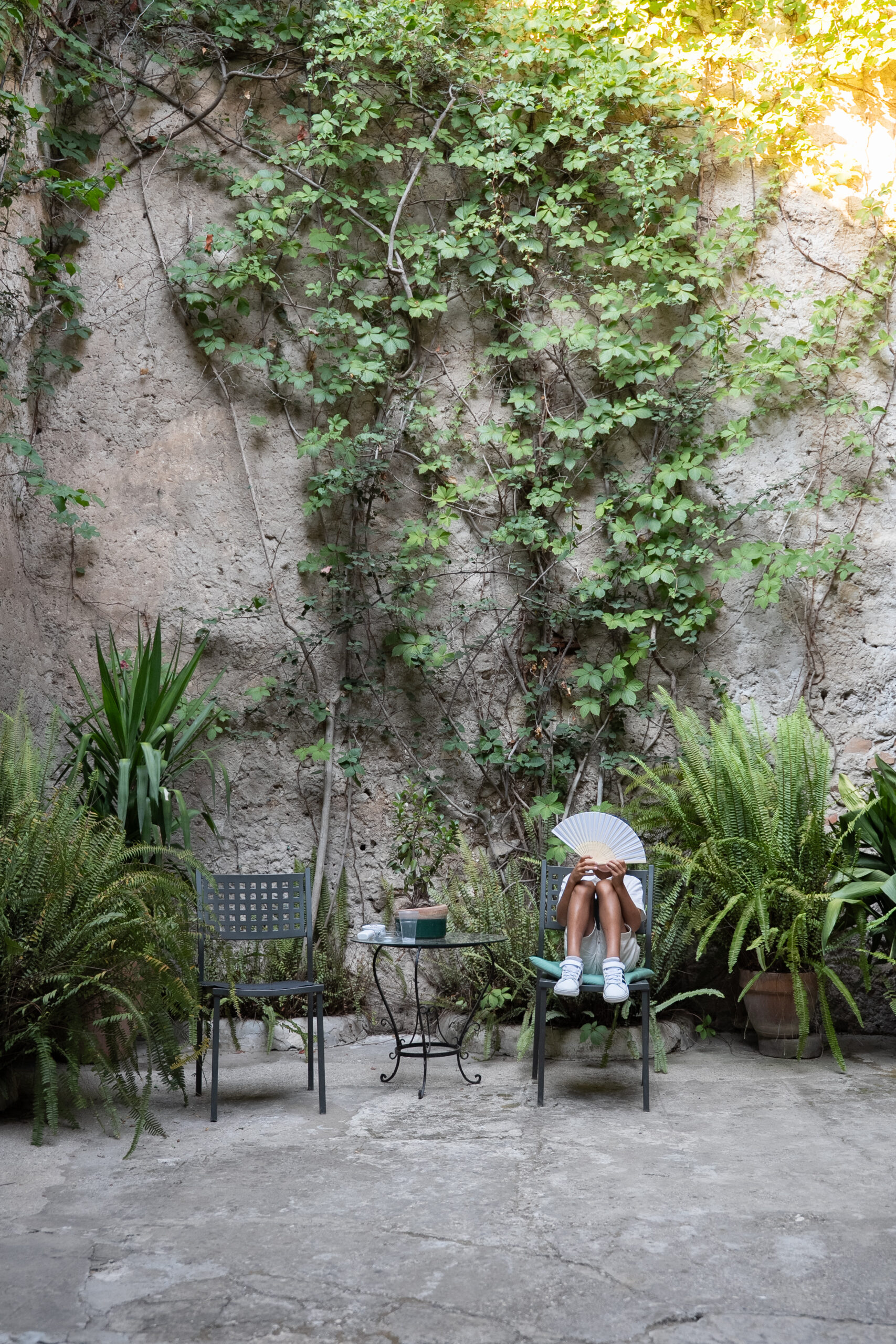 Wedding guest cooling down with a fan in the historic courtyard