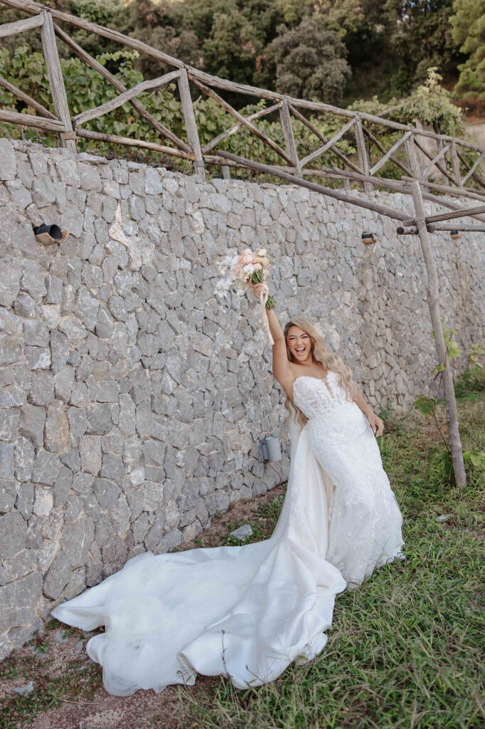 Bride posing beside a stone wall at Giardini del Fuenti