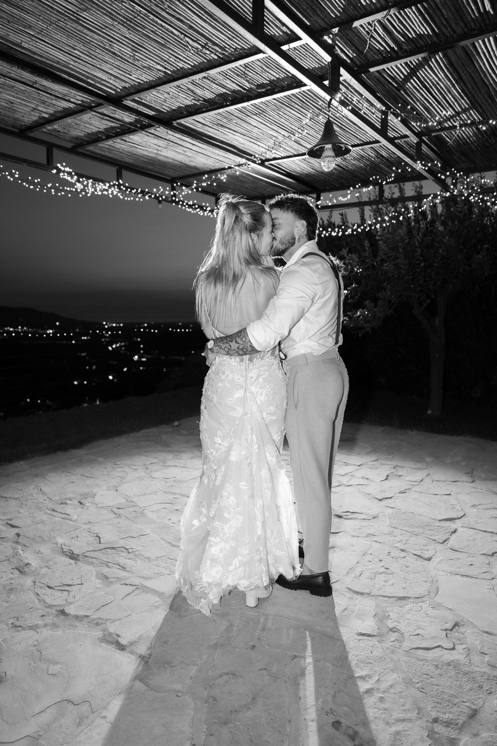 Adam and Polly embracing beneath the lights at Domus Laeta