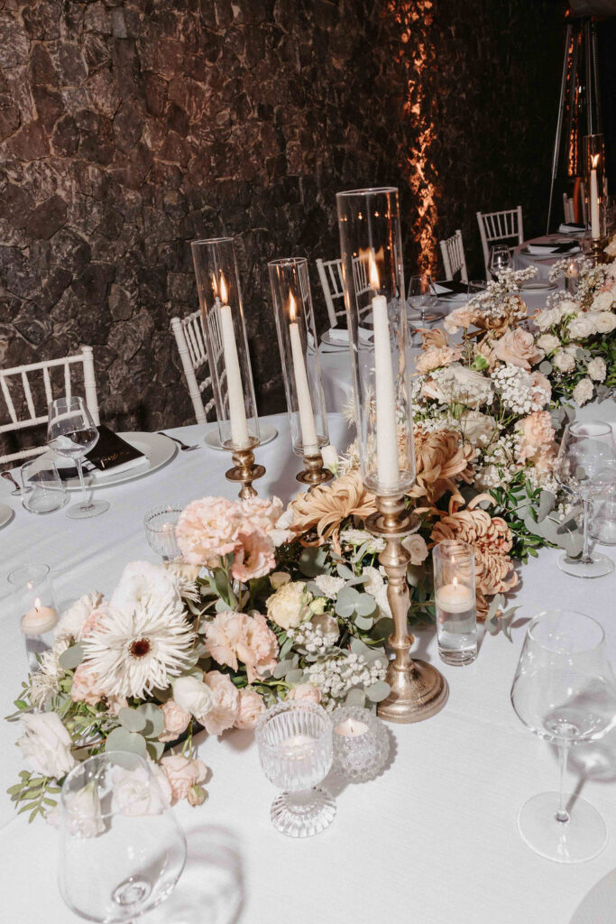 Newlyweds kissing behind the floral reception table