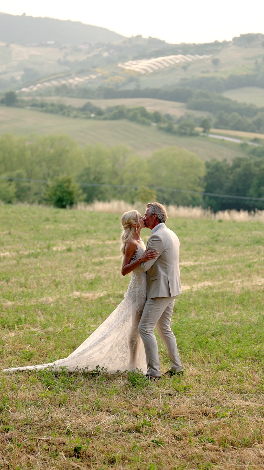 Gerben and Lonneke kissing in a meadow overlooking the Umbrian hills at Borgo Castello Panicaglia.