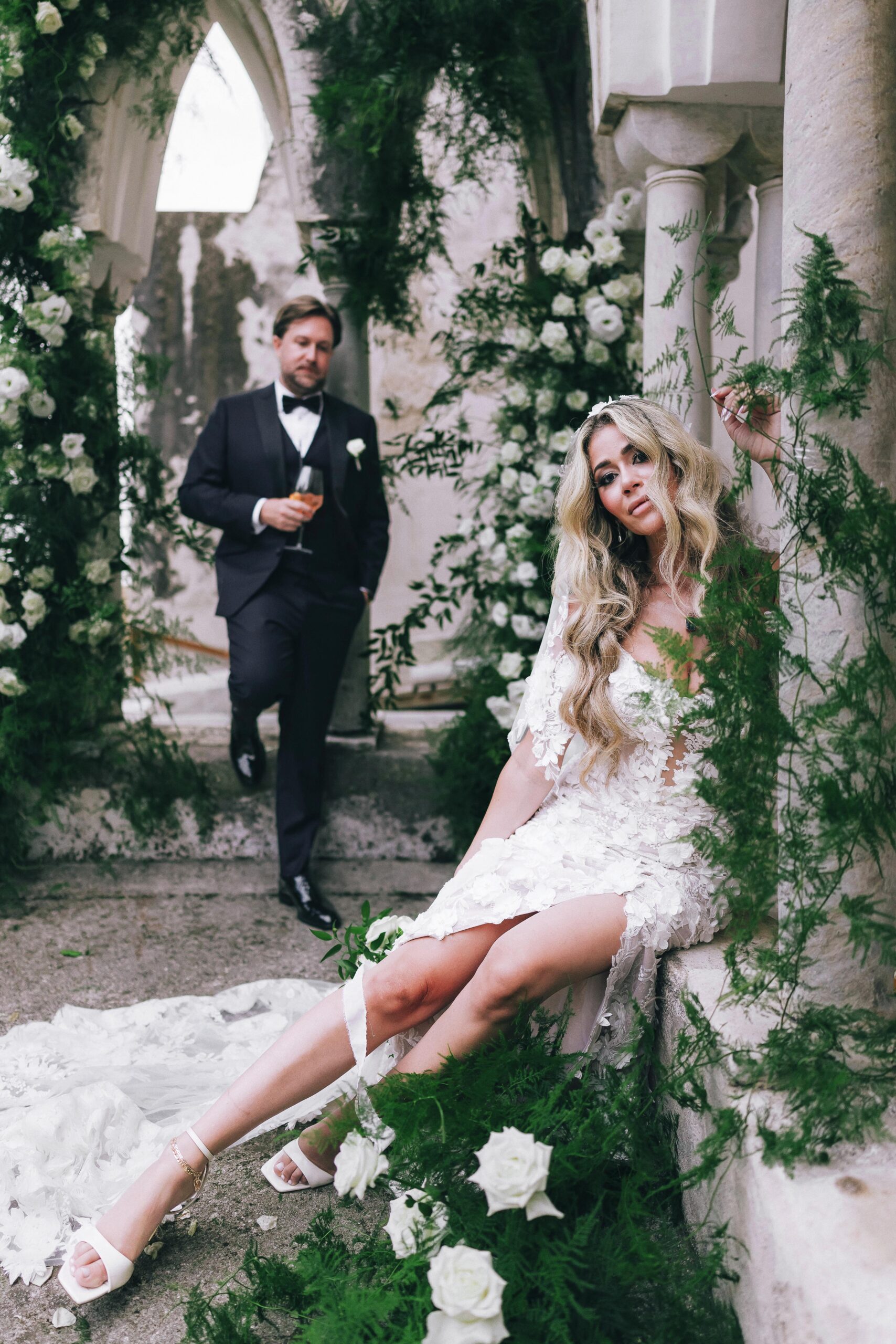 Editorial wedding portrait of Laura seated among greenery with Koury standing behind her
