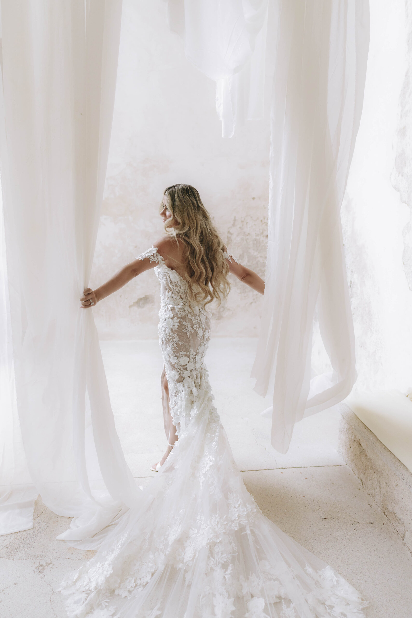Laura standing beside sheer curtains during her bridal preparation in Amalfi