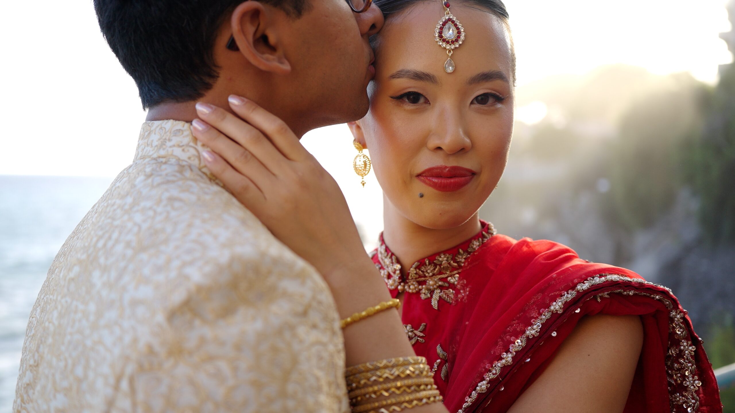 Sheh kissing Gaia&rsquo;s forehead as she wears a red embroidered outfit.