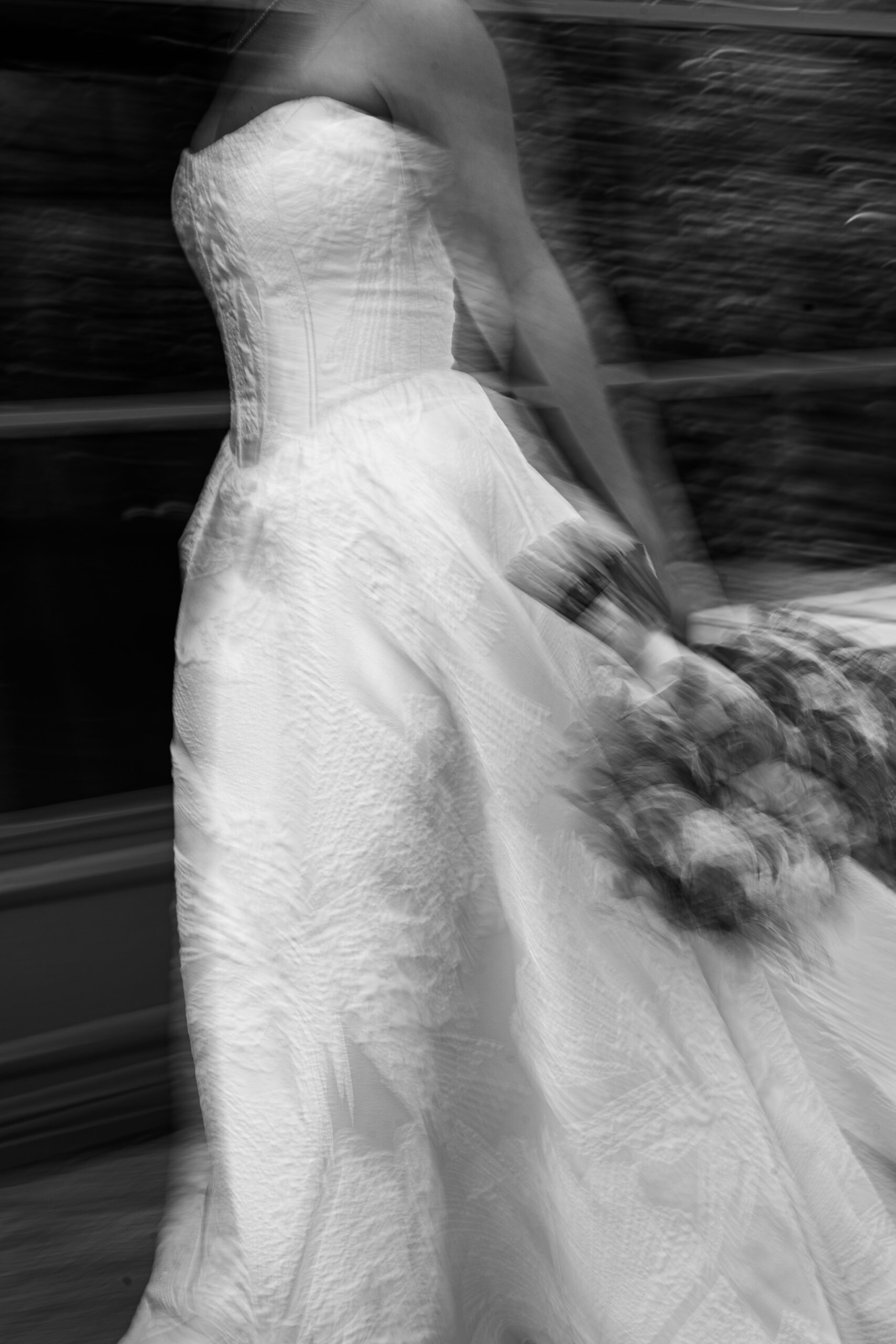 Black and white detail of Monica’s wedding dress and bouquet, with a sense of movement.