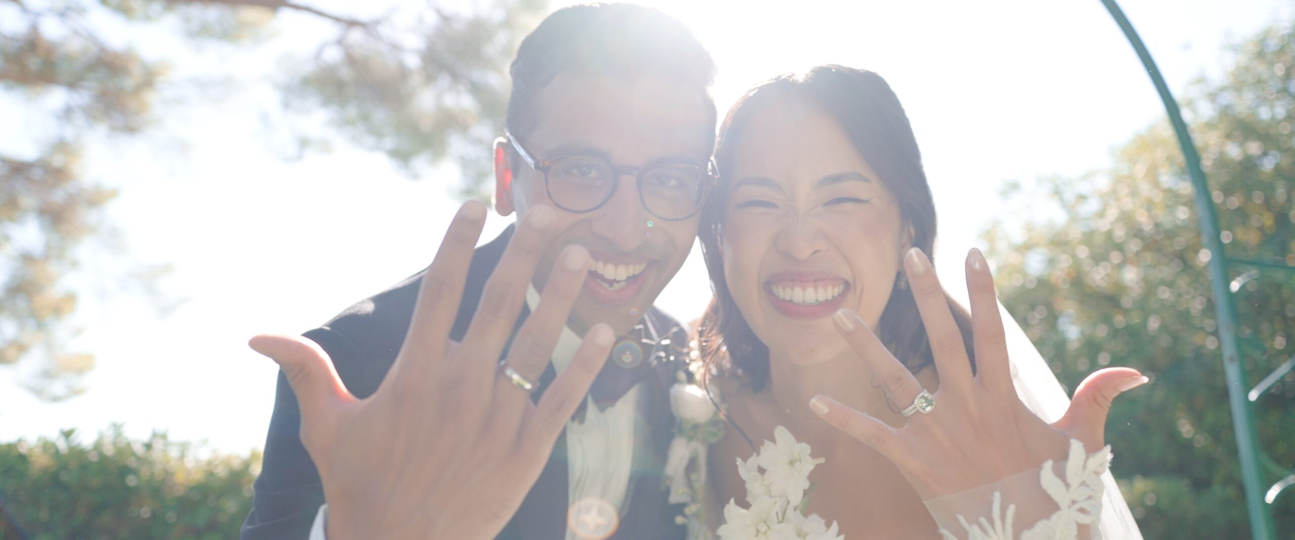 Gaia and Sheh laughing and showing their wedding rings.